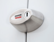 Close-up of a silver door handle with a small white oval badge attached, featuring red and black lettering.