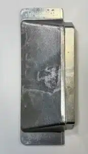 Shiny two-toned metal object with a rectangular body and flared ends, photographed upright on a light background.